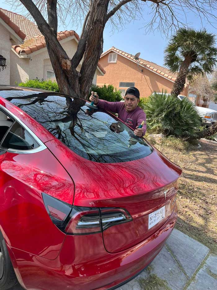 Windshield repair and glass placement on a red Tesla in Las Vegas